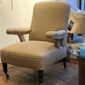 French chair with showing arms, covered in Taupe linen, with black turned legs and brass castors. C1940